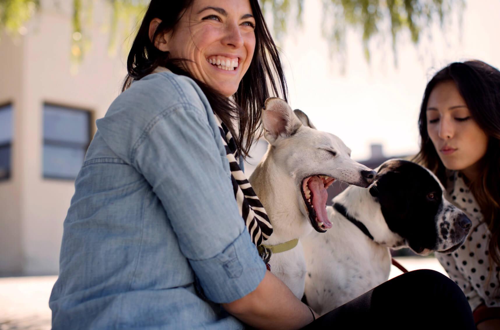 2 women hanging out with their dogs and smiling